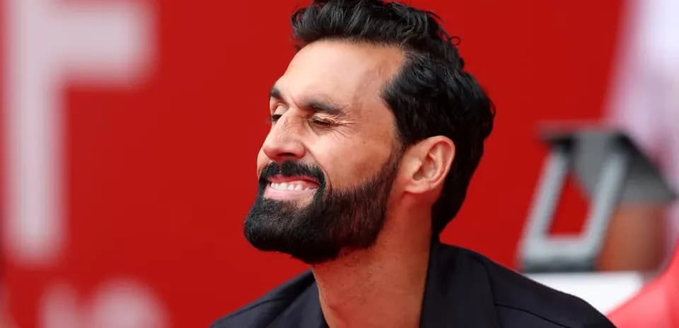 Man smiling while seated on bench with red background