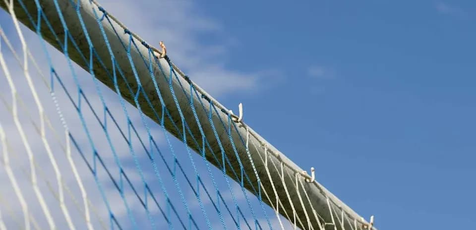 Close-up of a goal net against blue sky