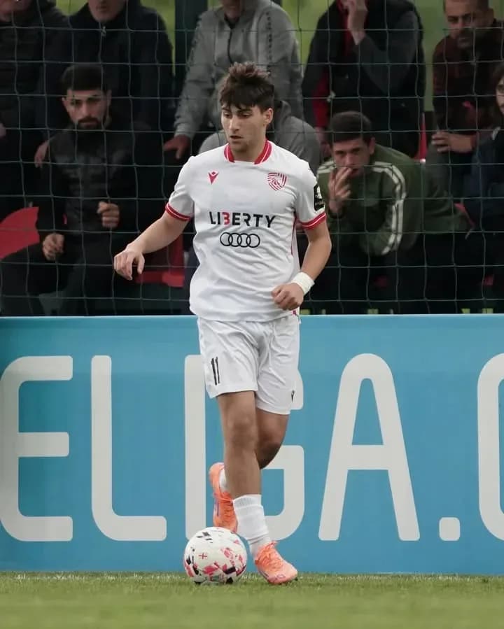Player in white kit dribbling ball on field
