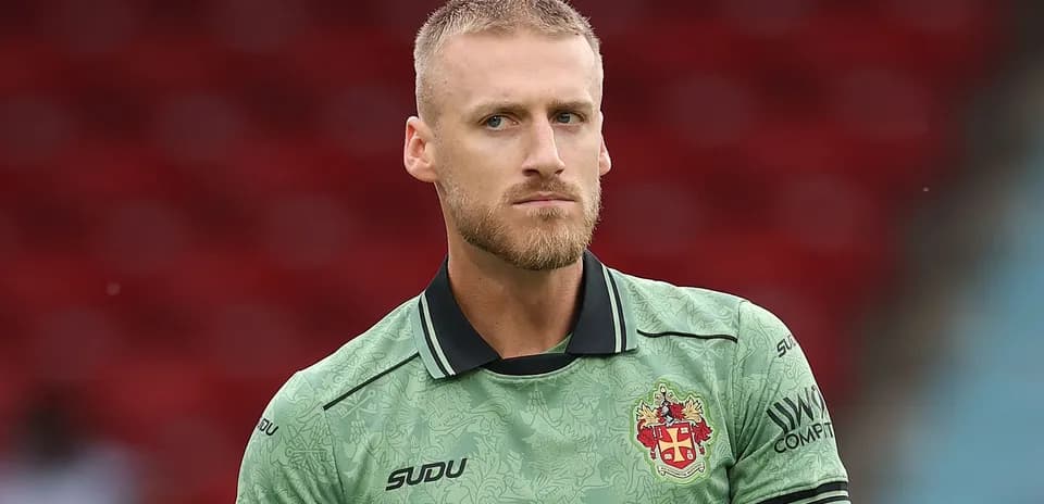 Goalkeeper in green kit during pre-match warm-up
