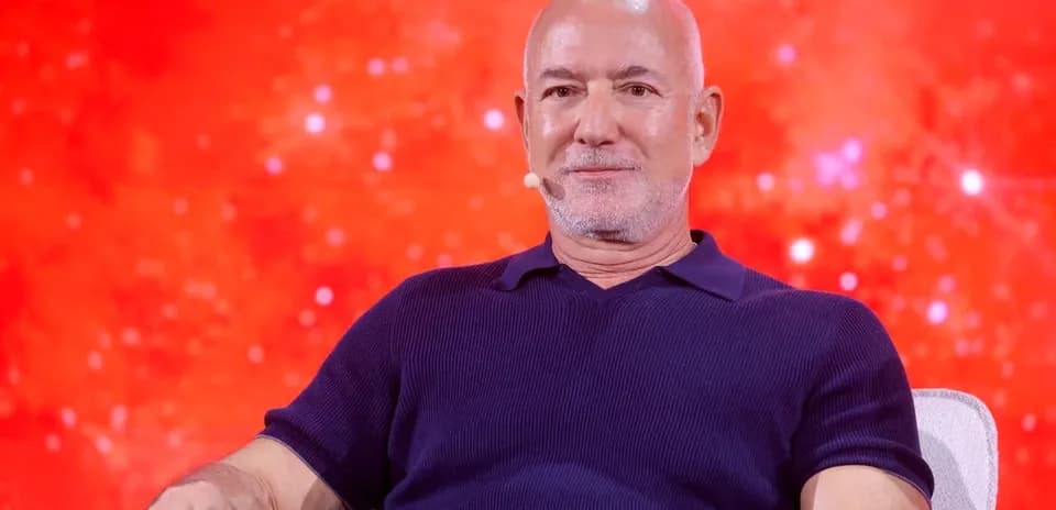 Person seated on stage with a red background
