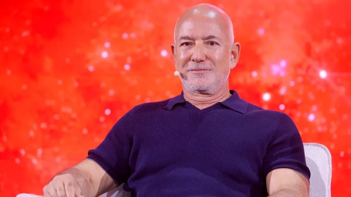 Person seated on stage with a red background