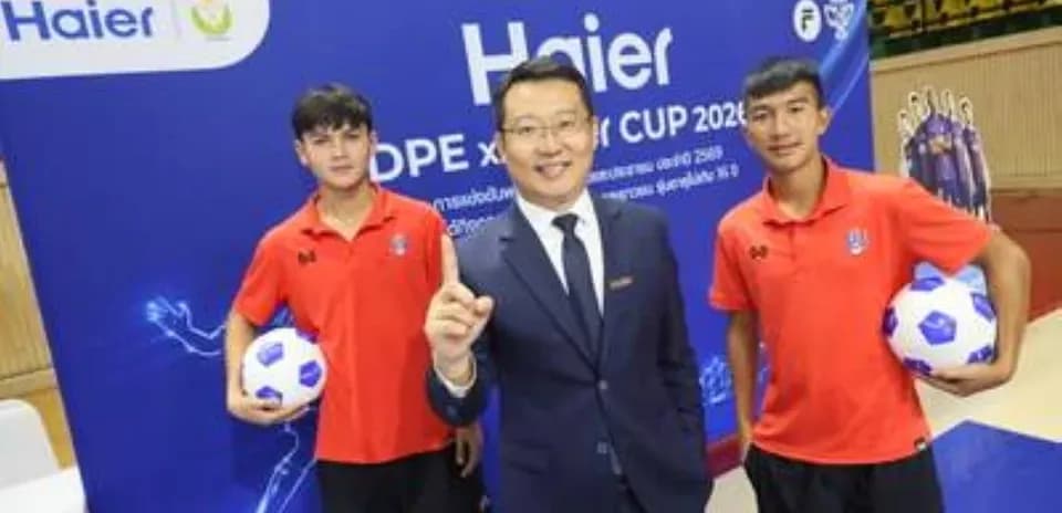 Two players and official posing with footballs