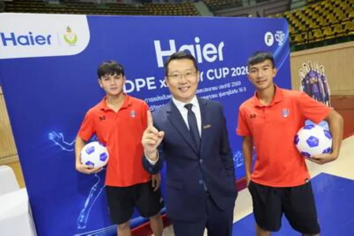 Two players and official posing with footballs