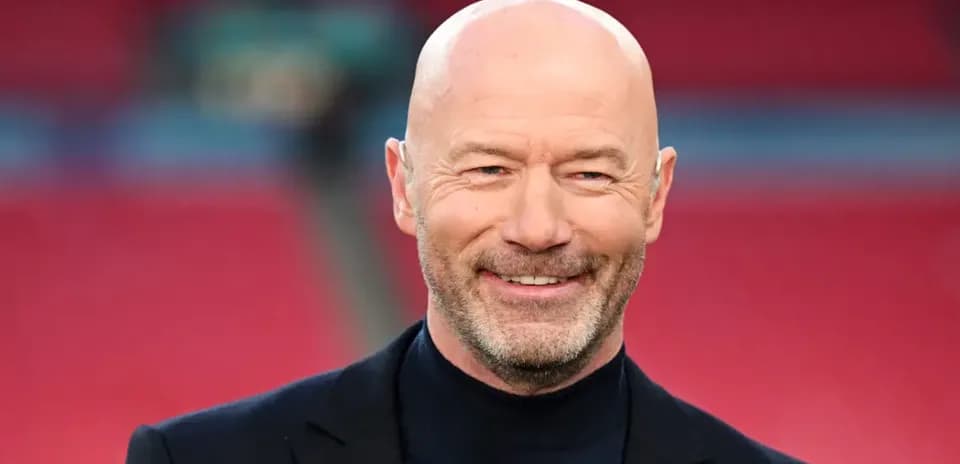 Bald man smiling in a suit at stadium