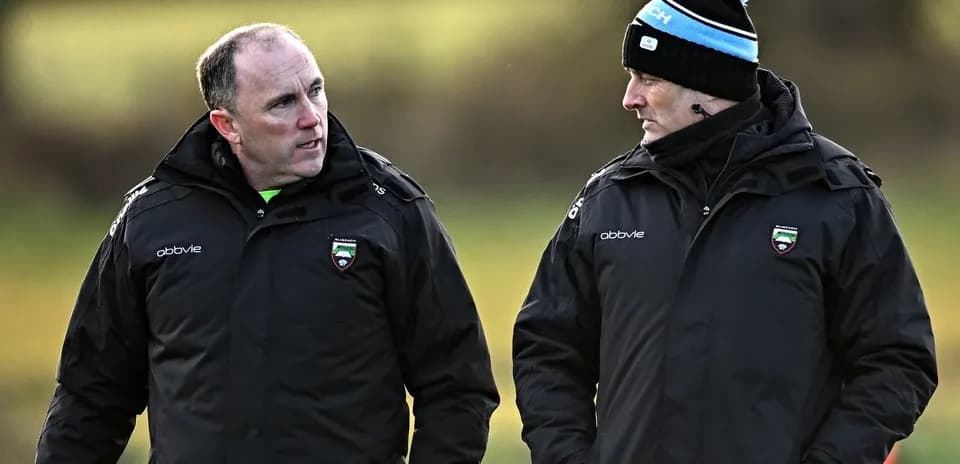Two coaches conversing on a training field