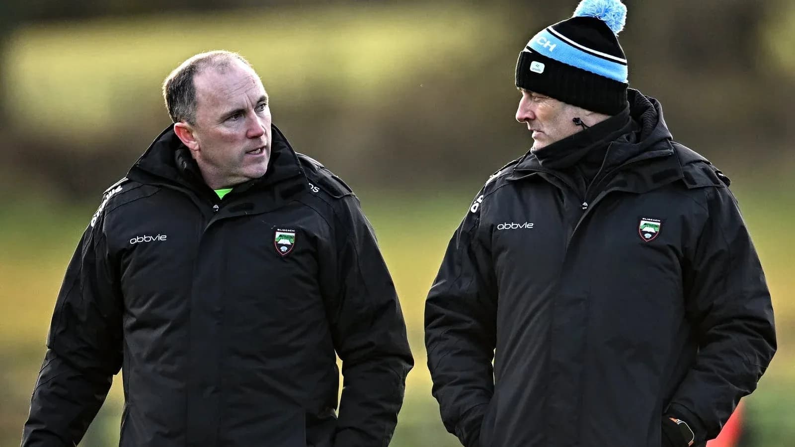 Two coaches conversing on a training field