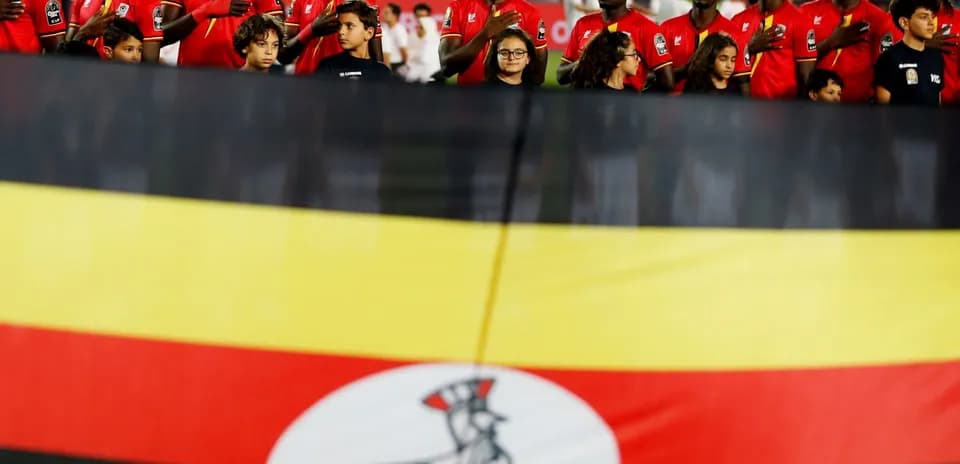 Ugandan team members singing national anthem with flag