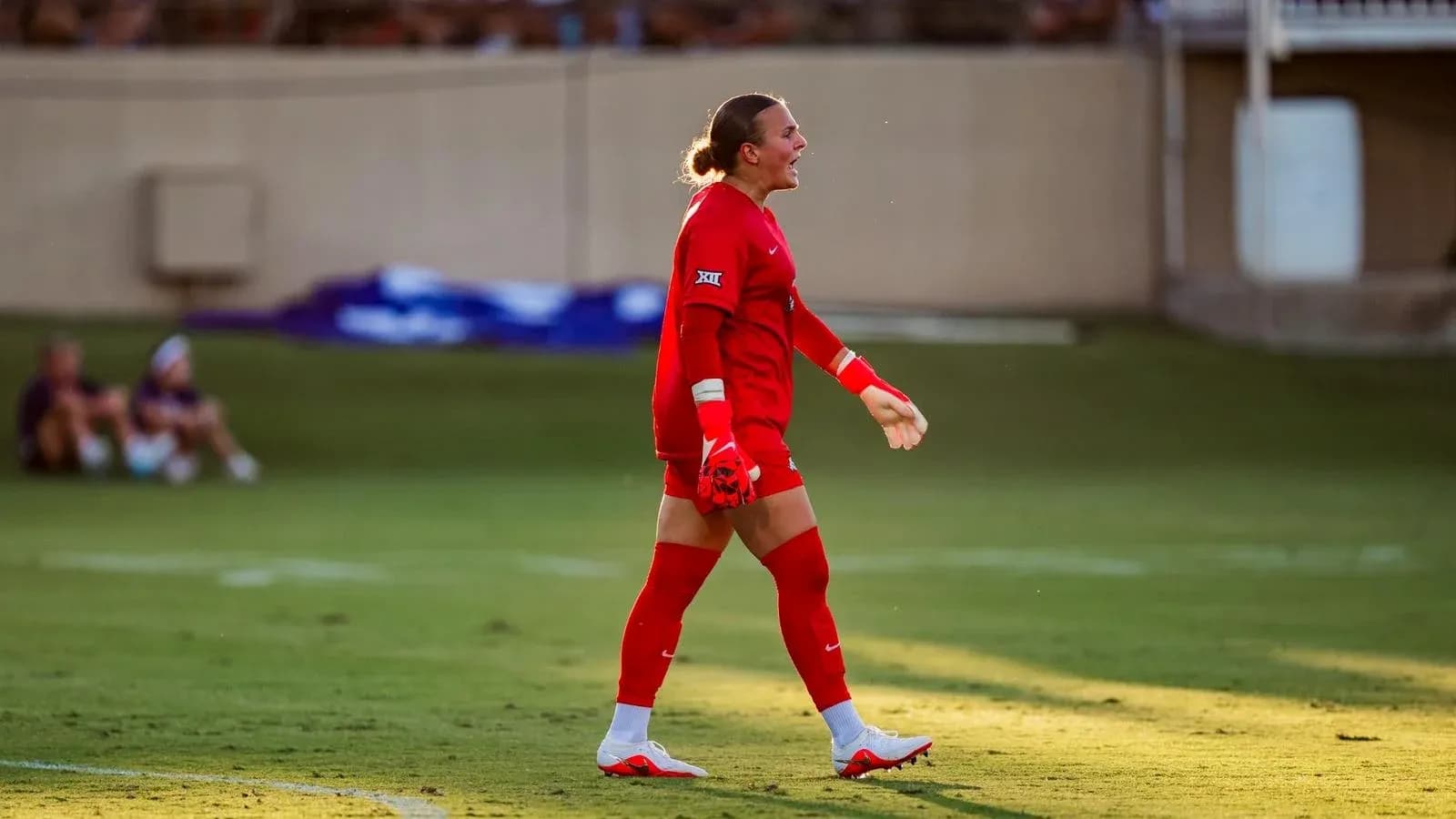 Goalkeeper in red uniform walking on the field