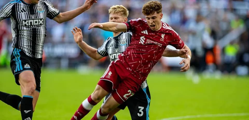 Newcastle player challenges Liverpool player for the ball