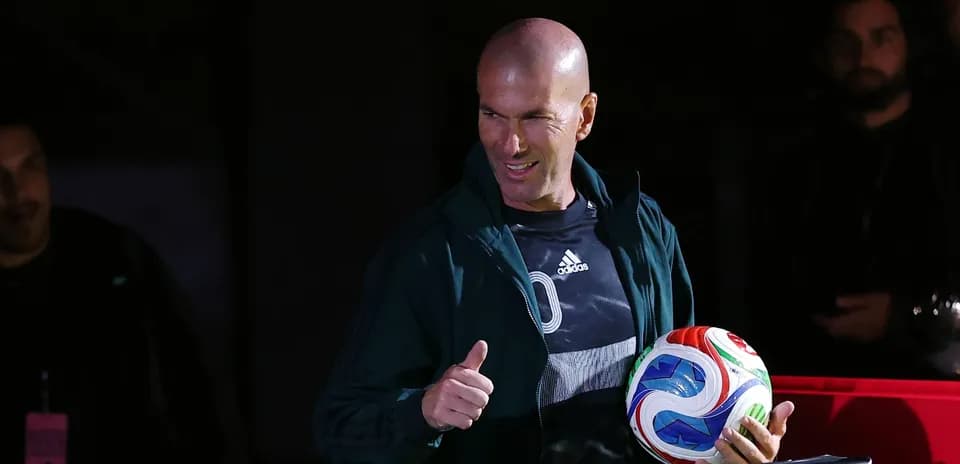 Zinedine Zidane holding a soccer ball with thumbs up