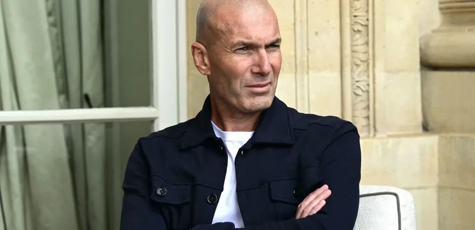 Man seated with arms crossed, looking thoughtfully
