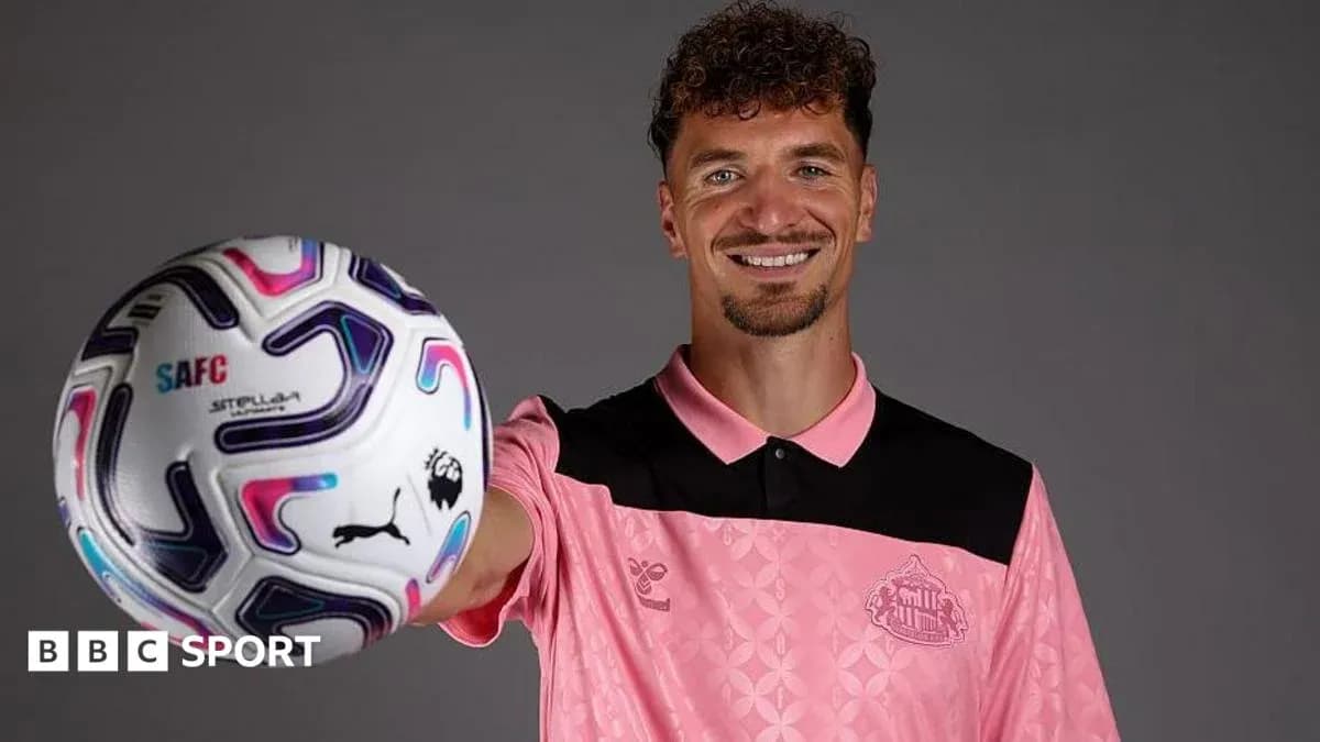 Player holding a football and smiling at camera