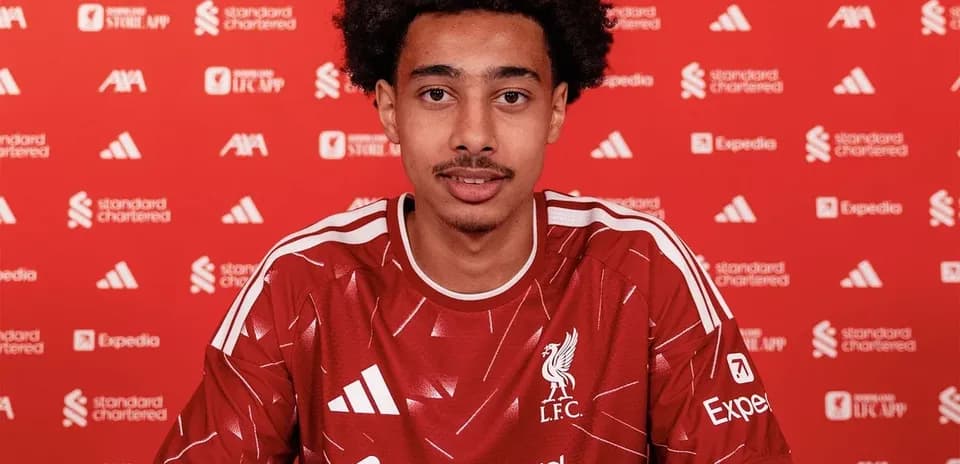 Player signing contract in Liverpool jersey at table