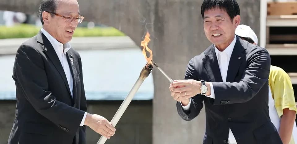 Two officials lighting a torch during ceremony