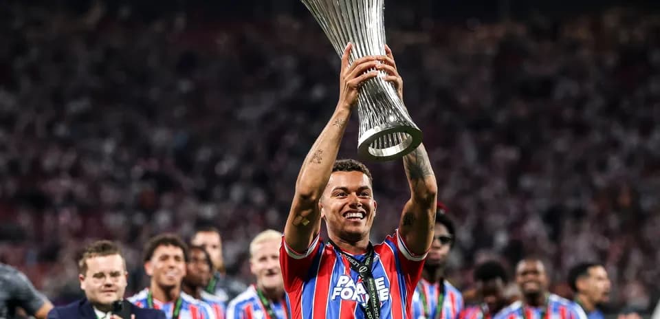 Player celebrating with trophy in stadium crowd