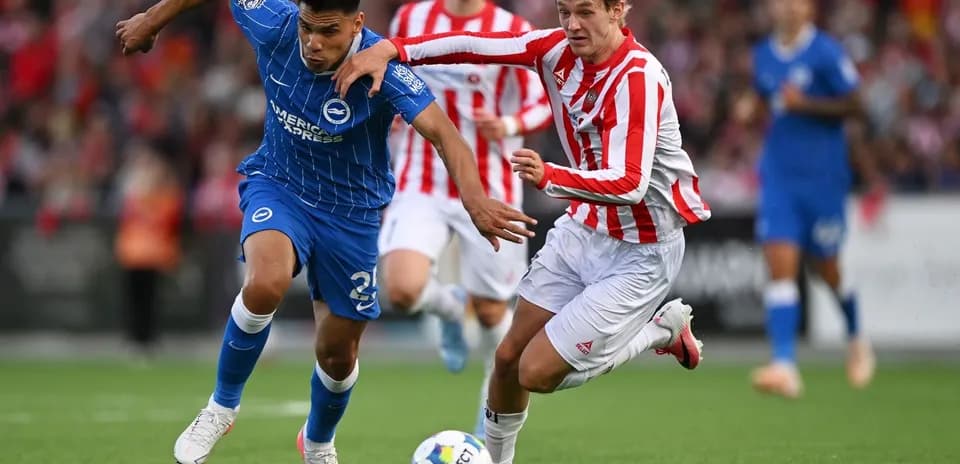Player in blue jersey tackled by opponent in red and white