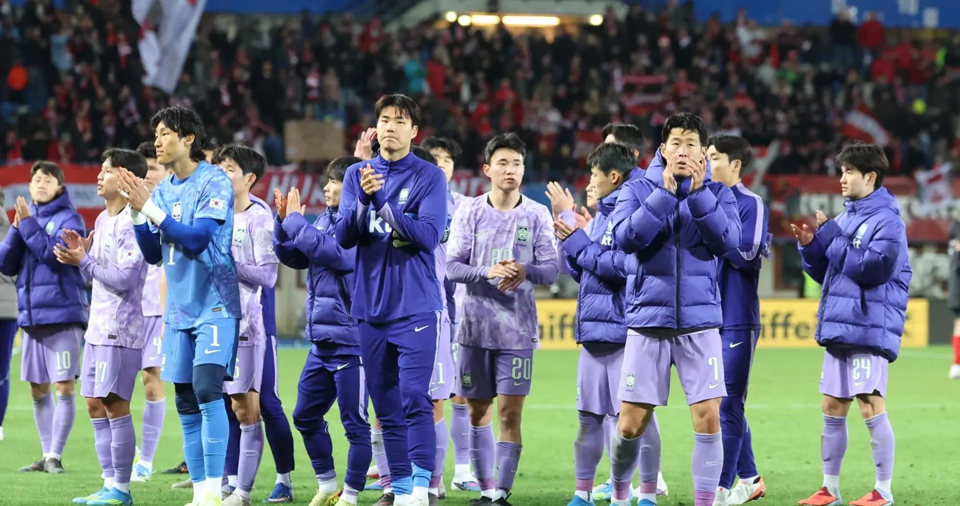 Team in purple jerseys applauding fans after match