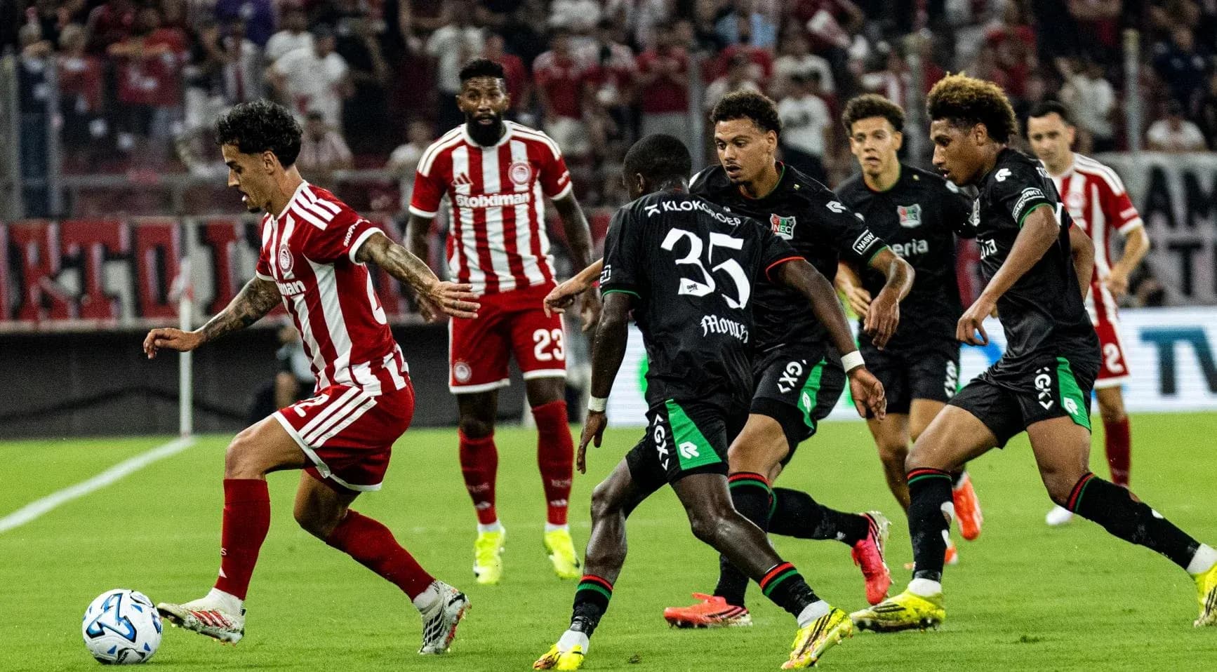 Olympiakos player dribbling against NEC defenders