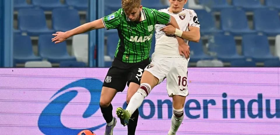 Sassuolo player challenged by Torino opponent