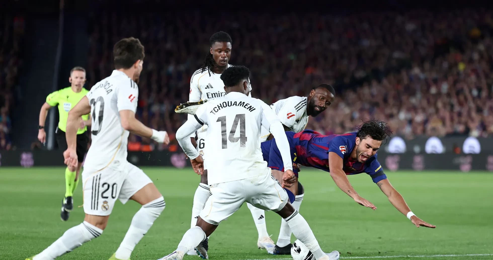 Barcelona player falling as Real Madrid defenders challenge