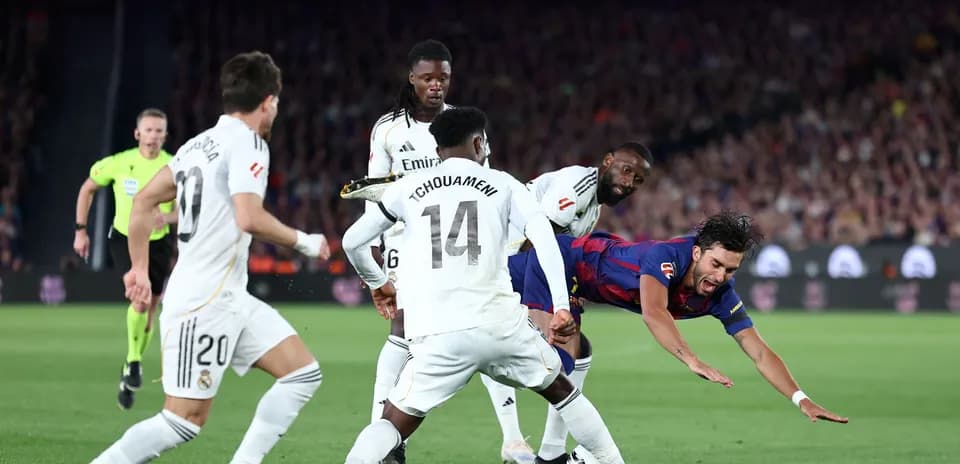 Barcelona player falling as Real Madrid defenders challenge