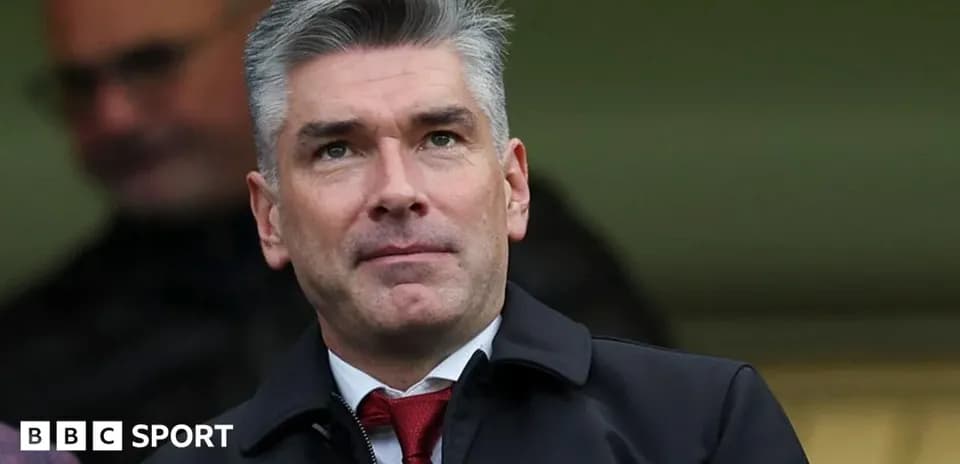 Man in a suit observing from the stands