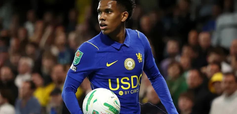 Player in blue kit holding a football on pitch