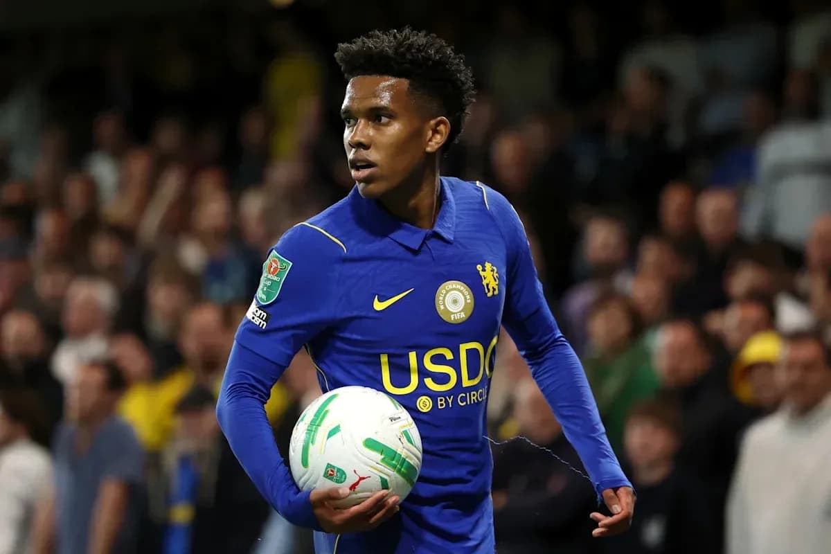 Player in blue kit holding a football on pitch