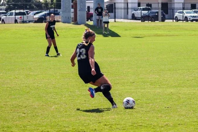 Player in black jersey kicking a soccer ball