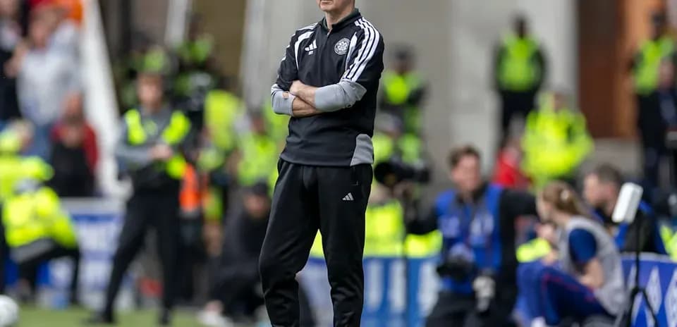 Coach observing match from sidelines with arms crossed