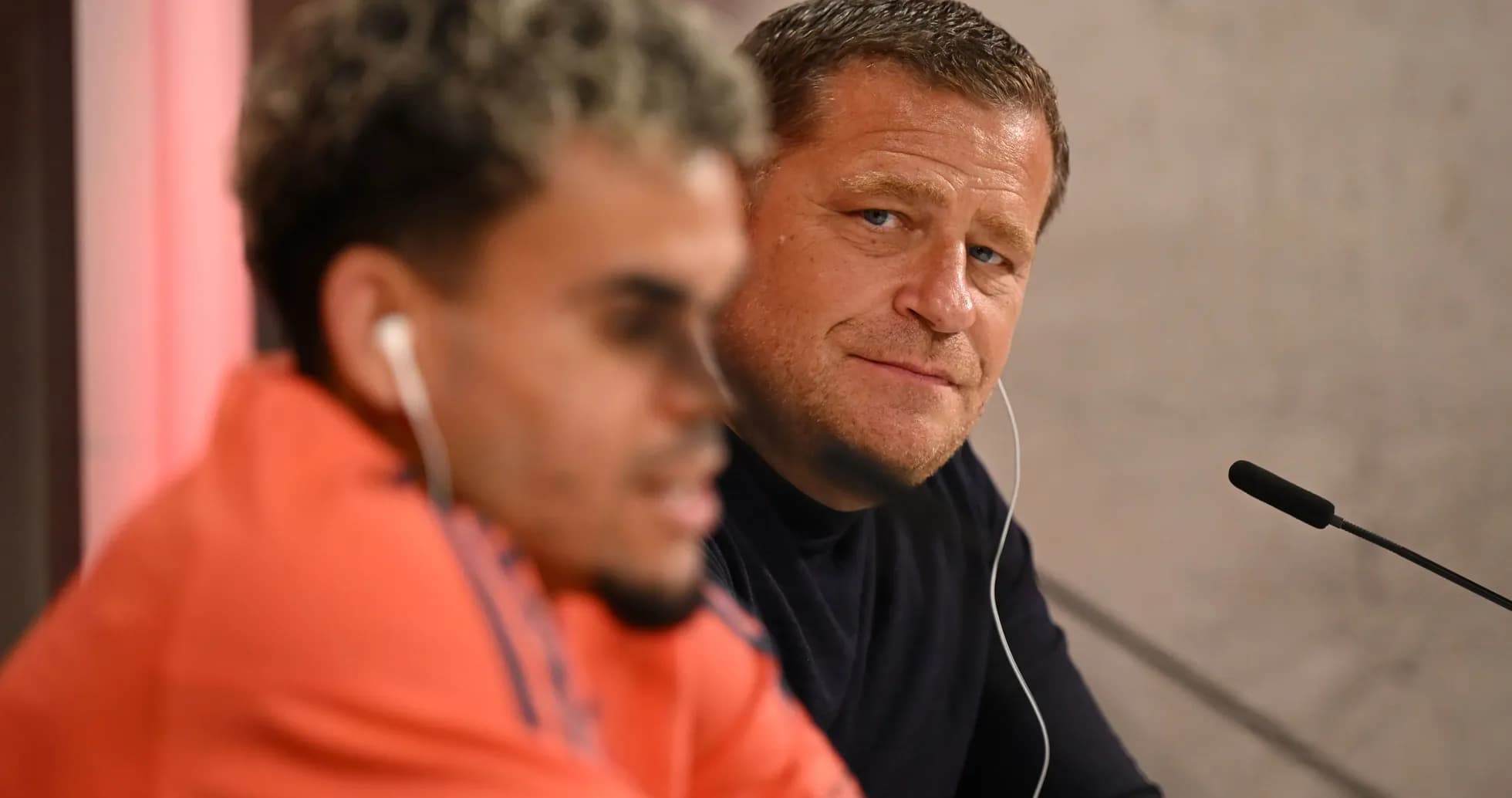 Two individuals at a press conference table