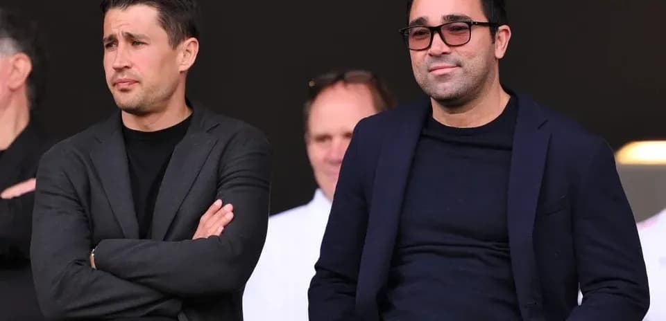 Two men seated in stadium stands observing event
