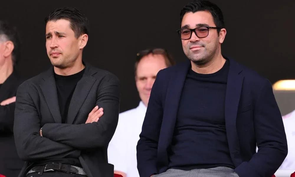 Two men seated in stadium stands observing event