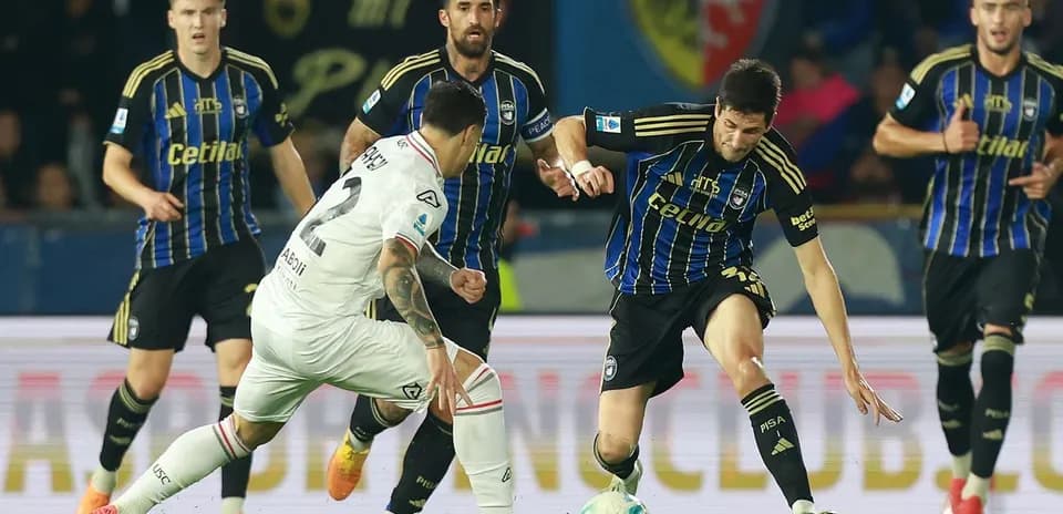 Cremonese player challenging Pisa opponent for ball