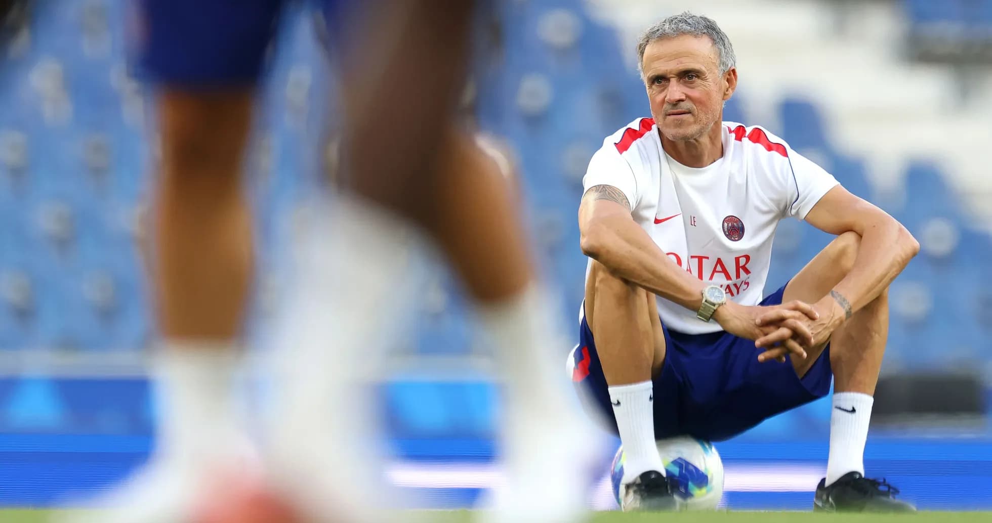 Coach squatting during training session on field