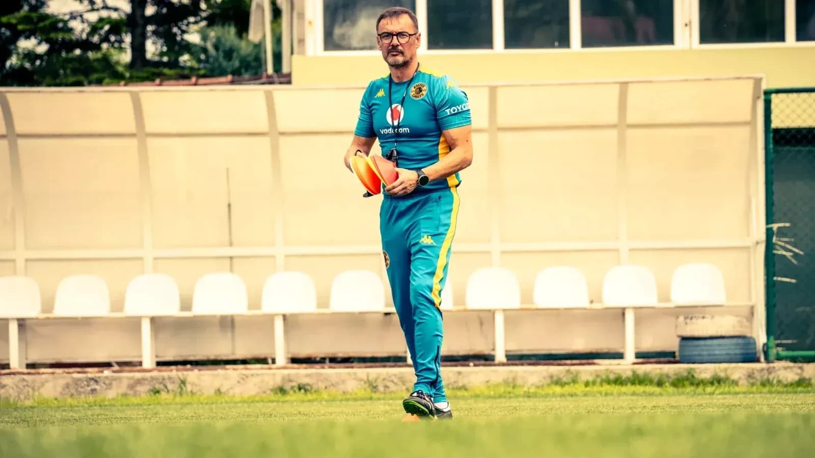 Coach walking on field holding training equipment