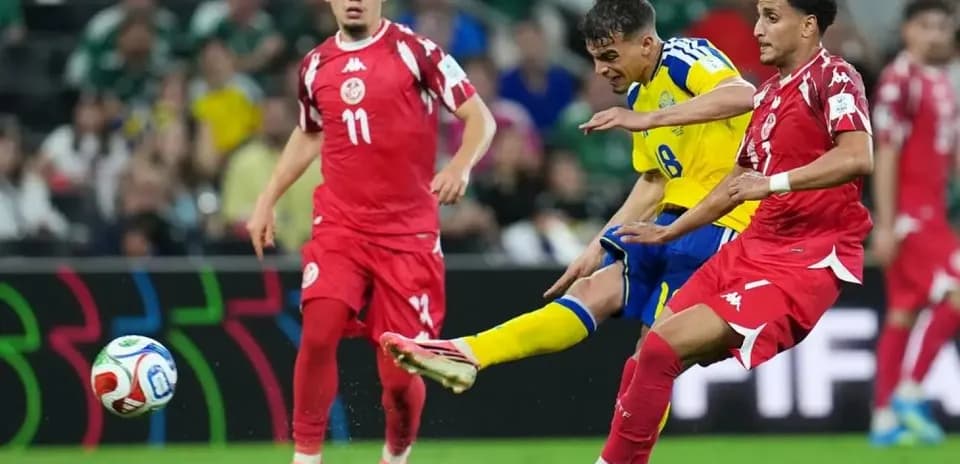 Sweden player kicking ball against Tunisia defenders