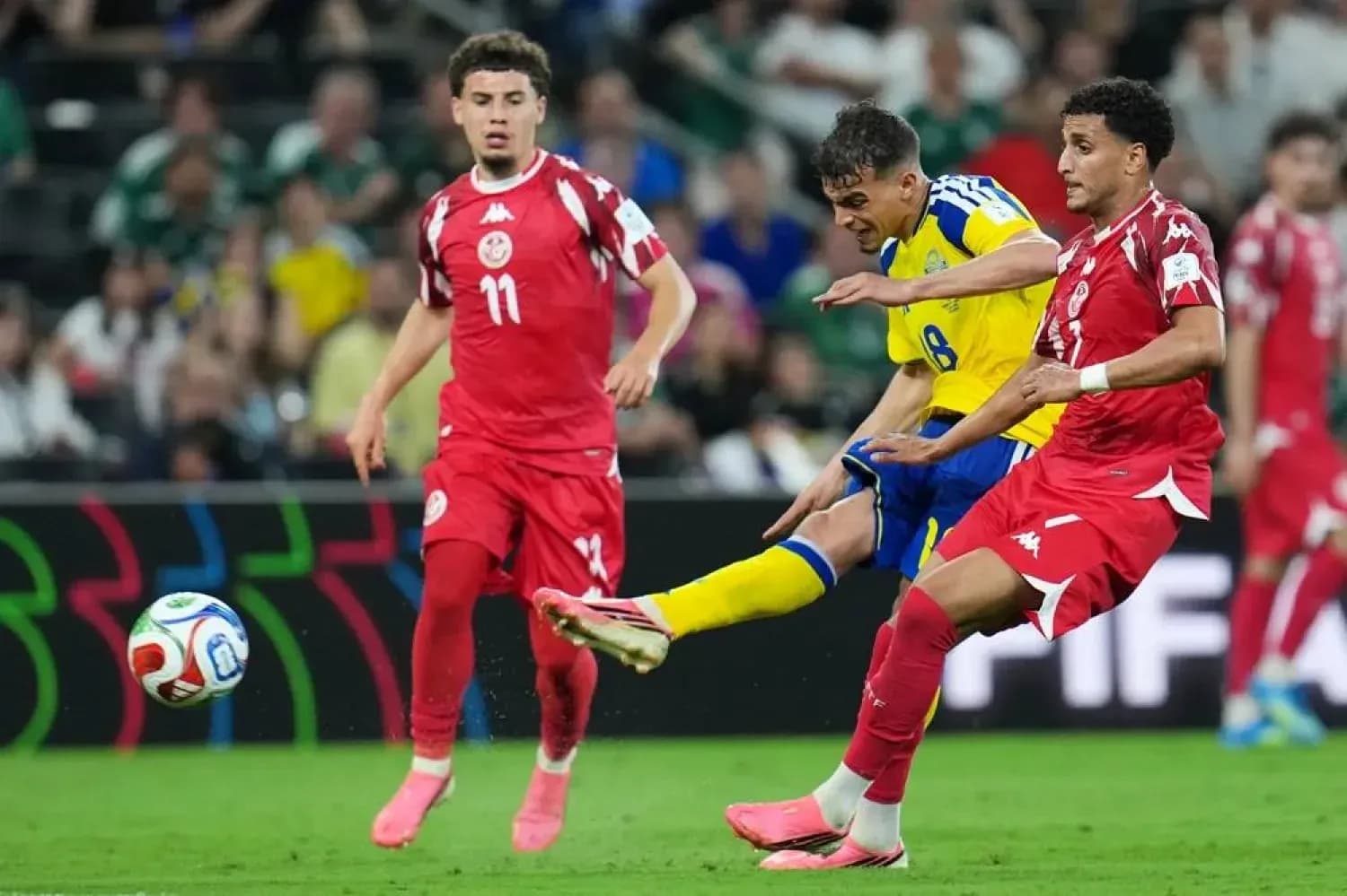 Sweden player kicking ball against Tunisia defenders
