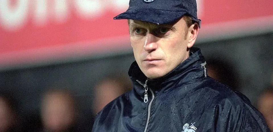 Coach in rain jacket at football match