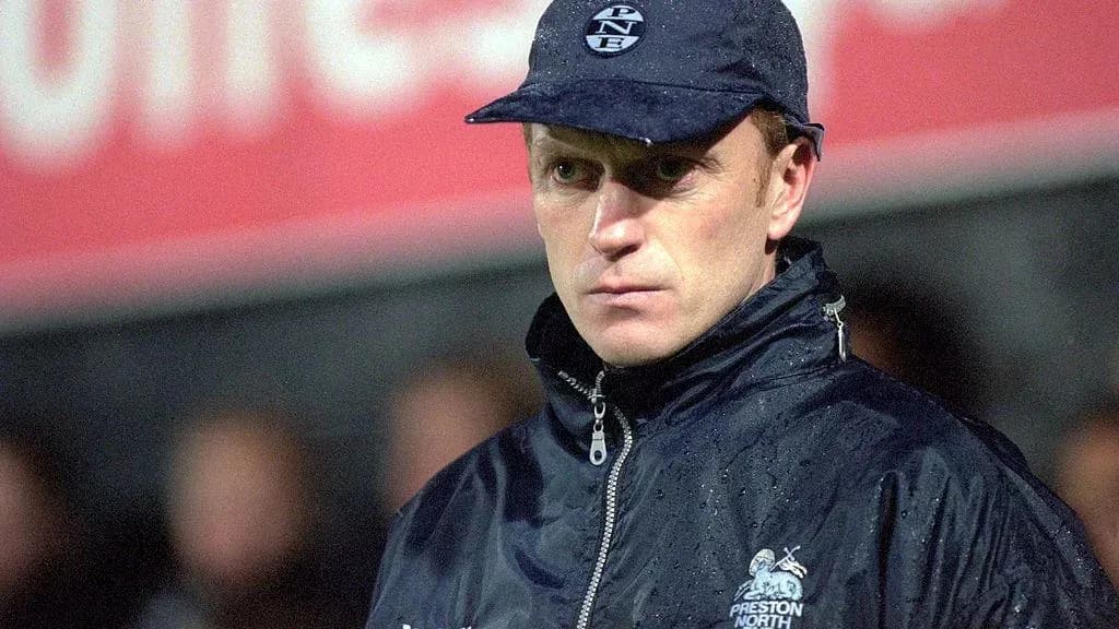 Coach in rain jacket at football match