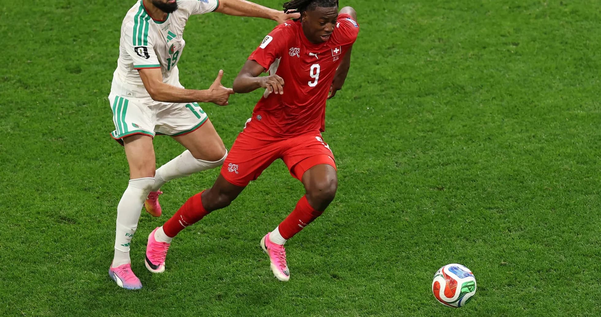 Player from Switzerland evading tackle by Algeria player