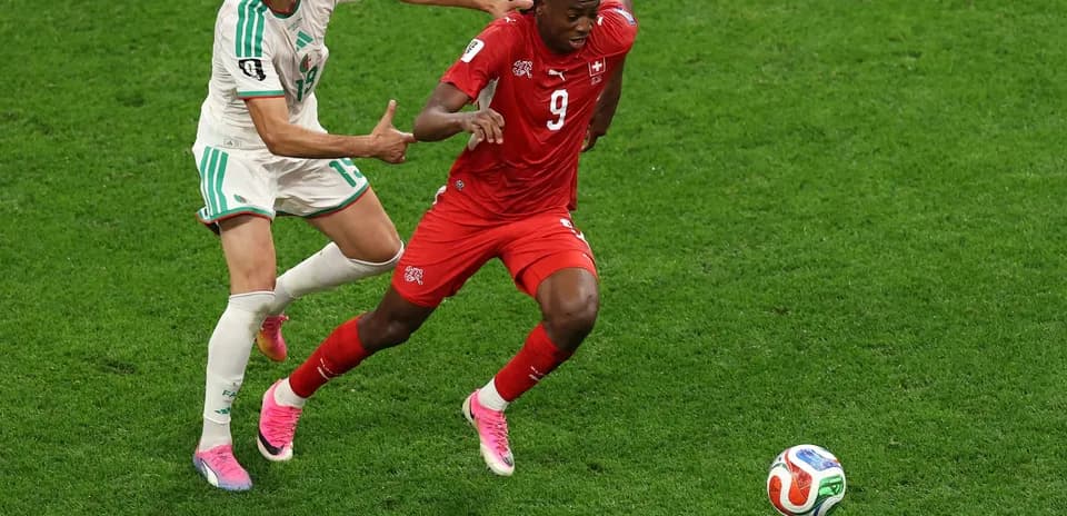 Player from Switzerland evading tackle by Algeria player