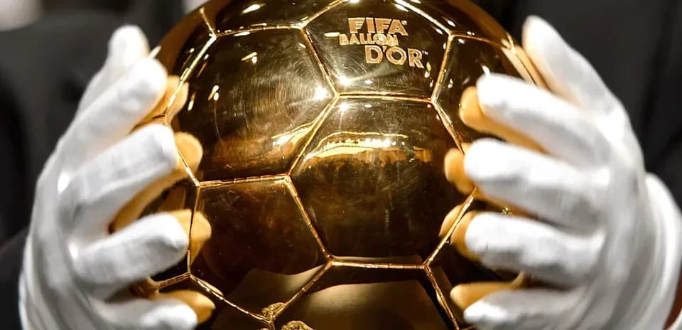 Person holding FIFA Ballon d'Or trophy with gloves