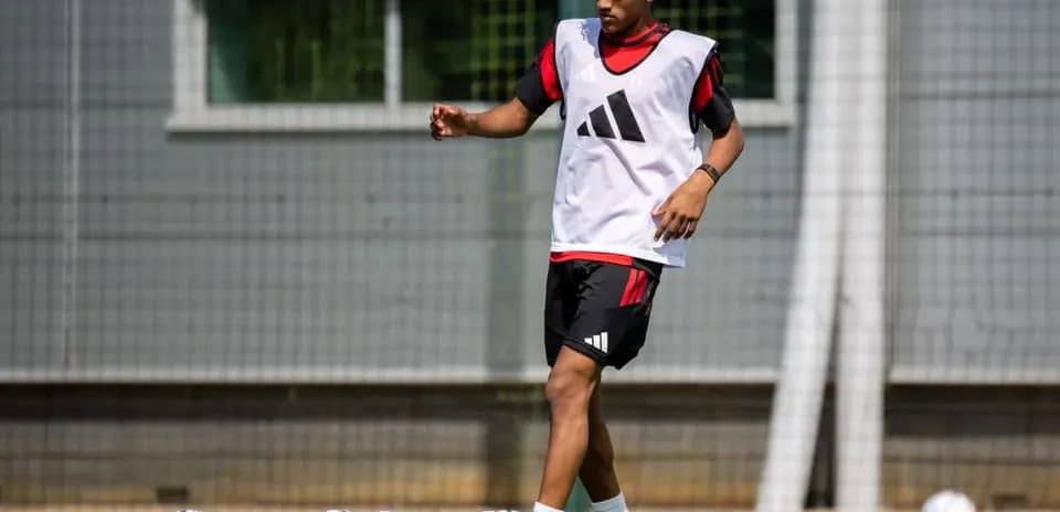 Player training on pitch with footballs nearby