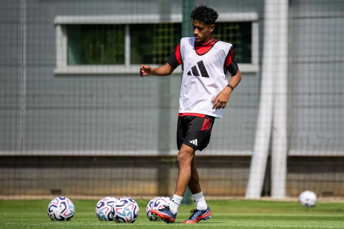 Player training on pitch with footballs nearby