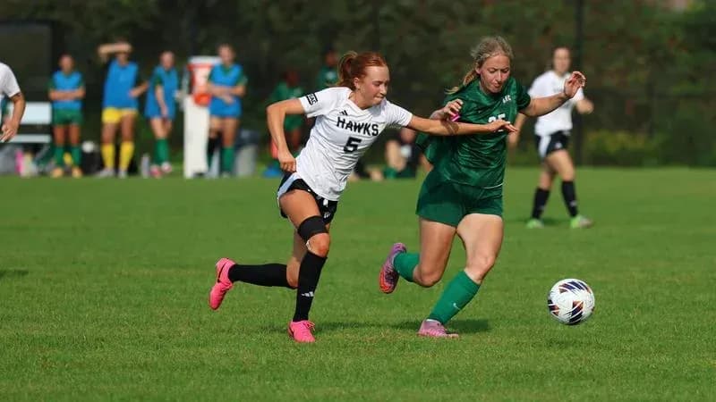 Player in white chasing the ball from player in green