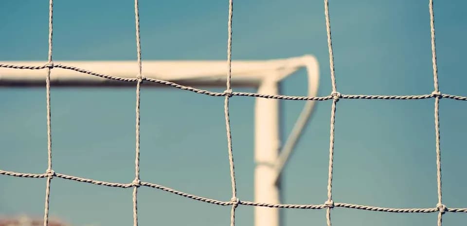 Close-up of a soccer goal net against blue sky