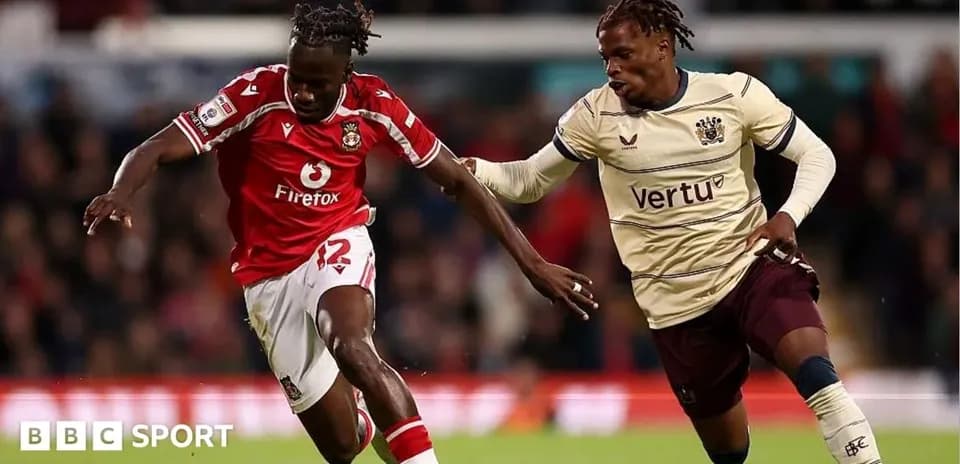 Player in red dribbling past opponent in beige kit