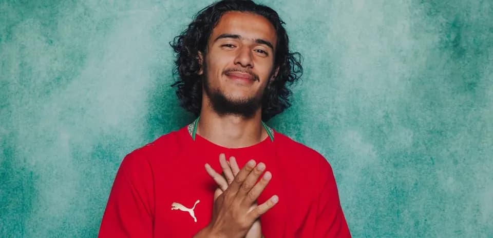 Player in red jersey smiling with hands clasped